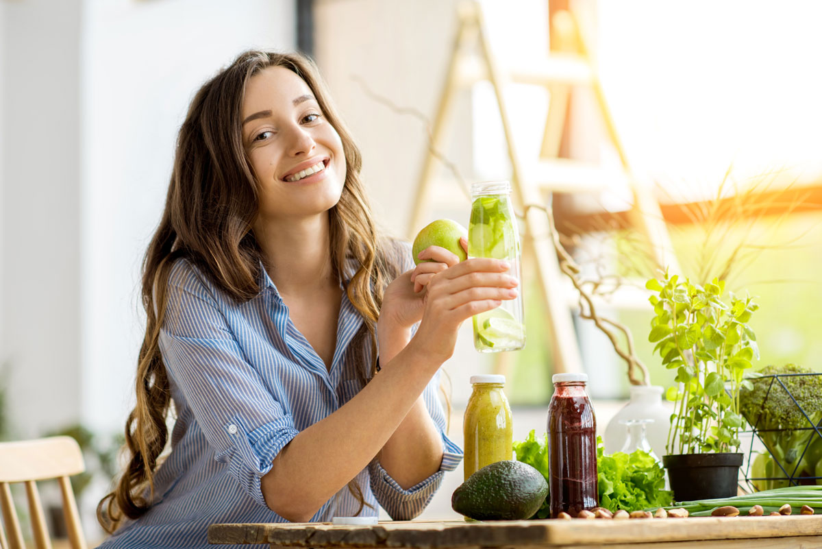 Beautiful happy woman sitting with drinks and healthy green food